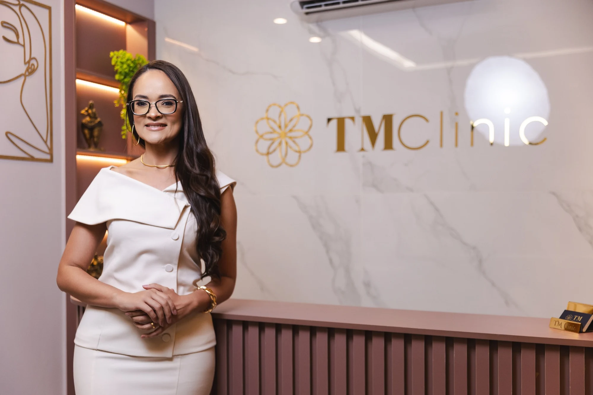 Dra. Thais na recepção da TM Clinic, ao lado da marca